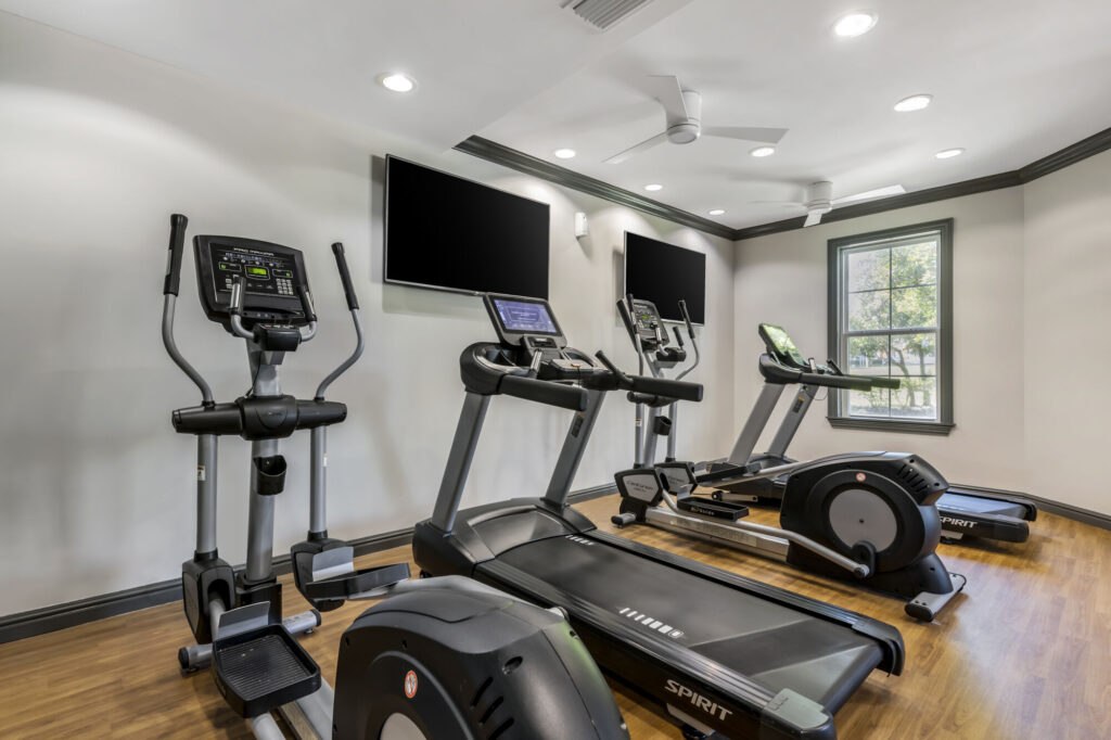 fitness center with cardio machines and TVs