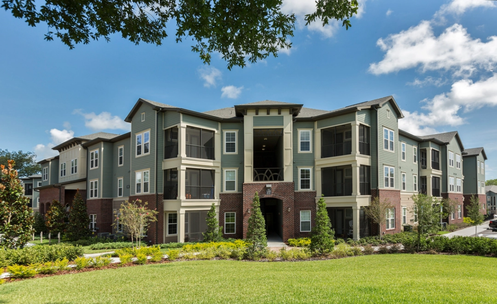Building exterior with screened balconies, lots of trees and landscaping