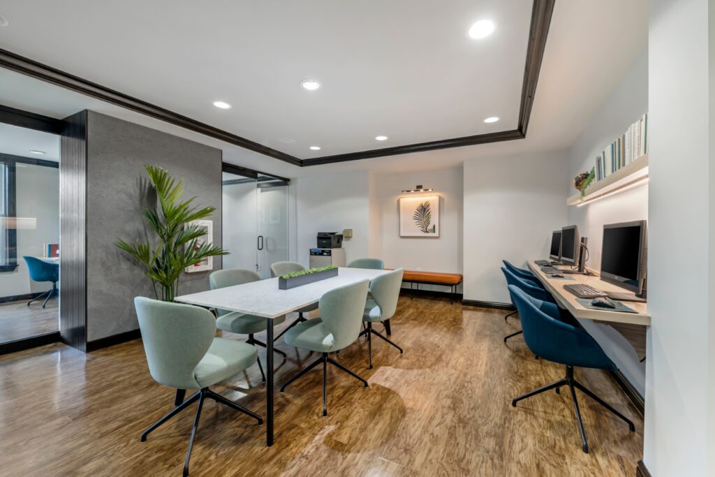 Business center conference room with computers, table seating, and wood-style flooring