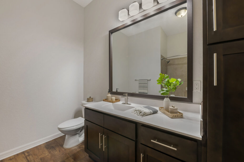Bathroom with toilet, single sink, wood-style flooring, and large mirror