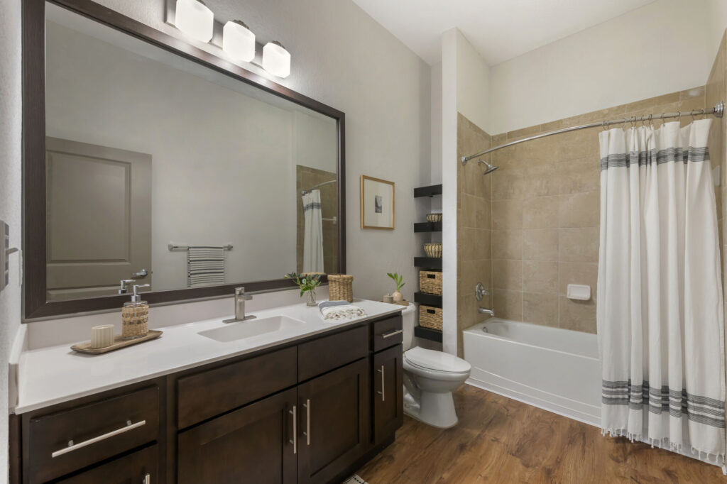 Bathroom with toilet, tub/shower combo, single sink, wood-style flooring, and built in shelves