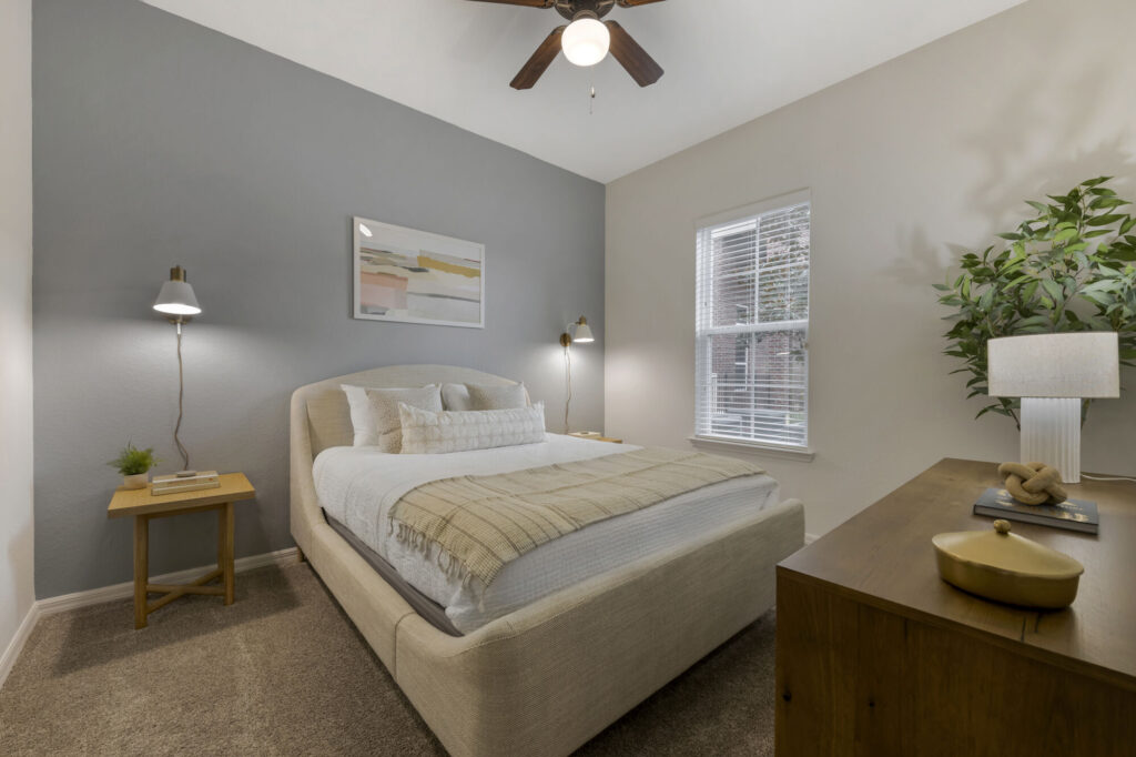 Bedroom with ceiling fan, carpet flooring and grey accent wall