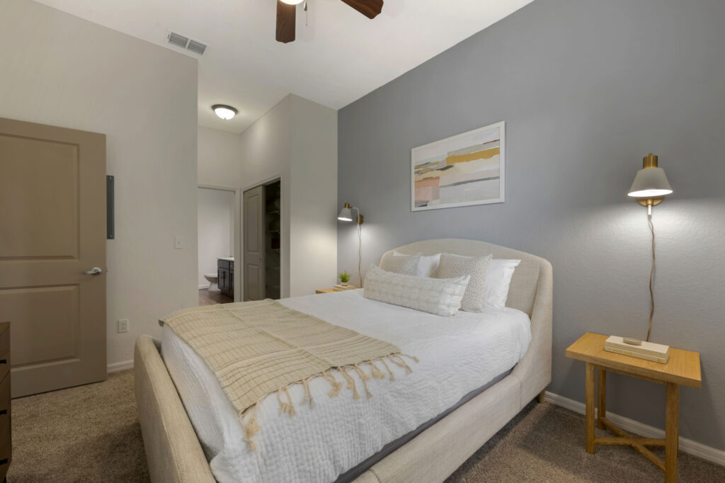 Bedroom with ceiling fan, carpet flooring and grey accent wall