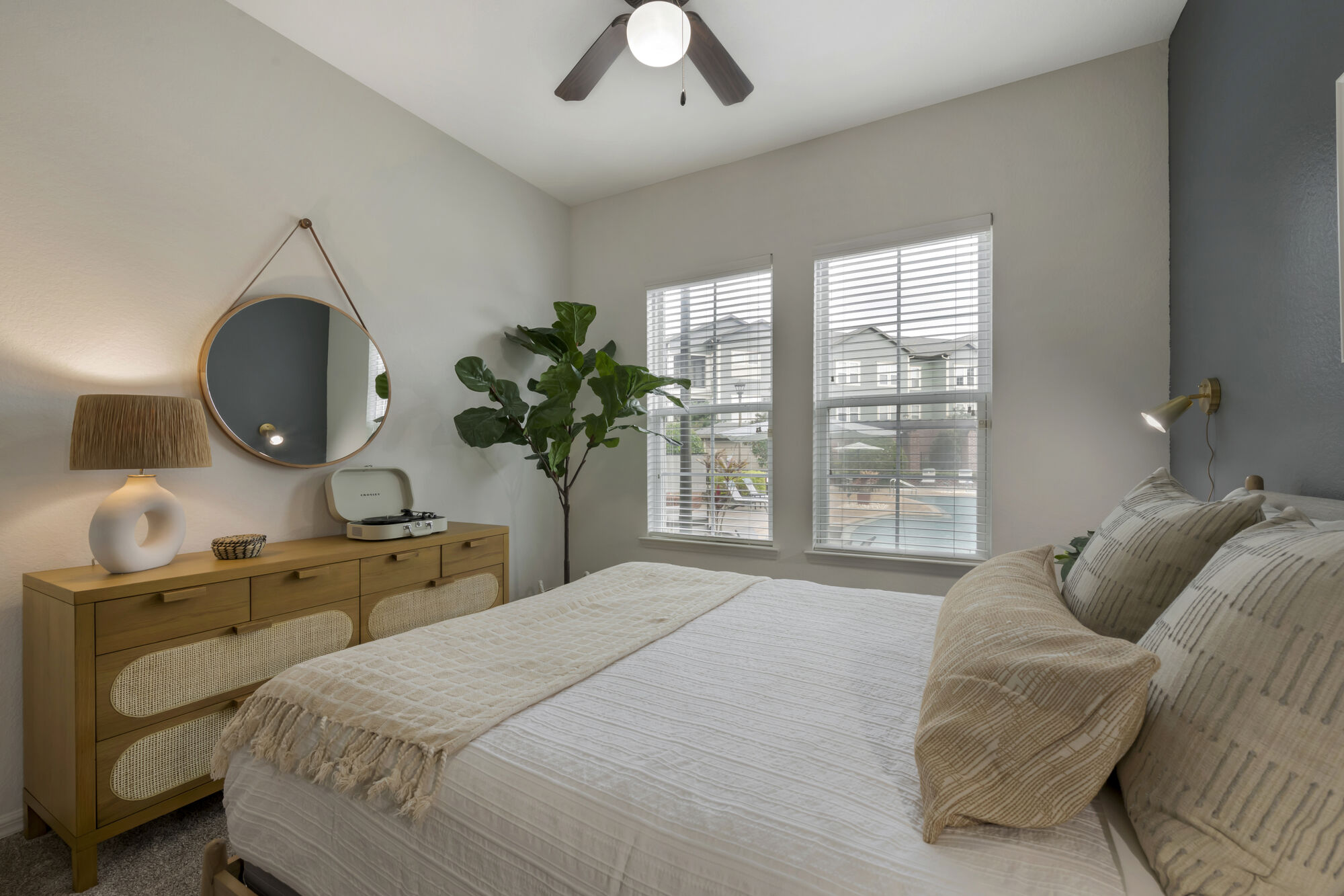 Bedroom with large windows, ceiling fan, carpet flooring and blue accent wall