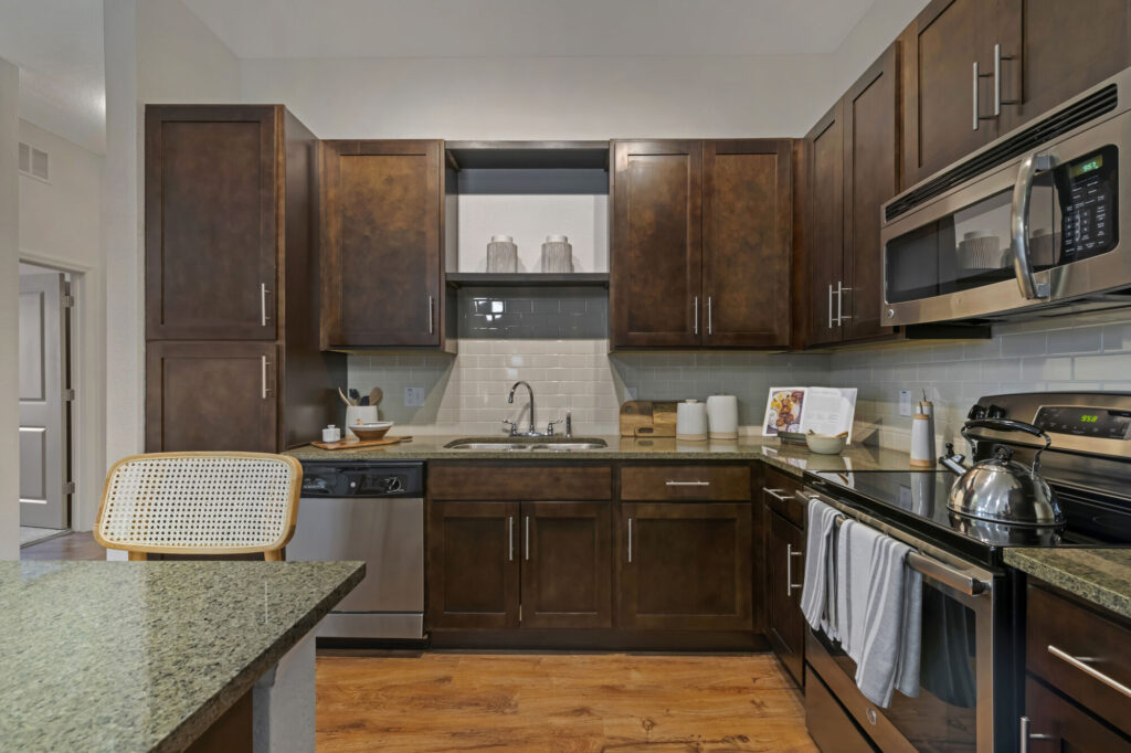 Kitchen with stainless steel appliances, granite countertops, wood-style flooring, and tile backsplash