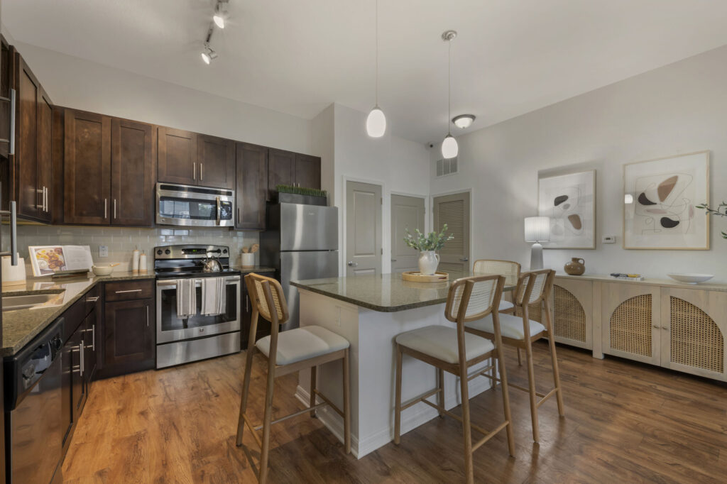 Kitchen with stainless steel appliances, granite countertops, tile backsplash, wood-style flooring, and island seating
