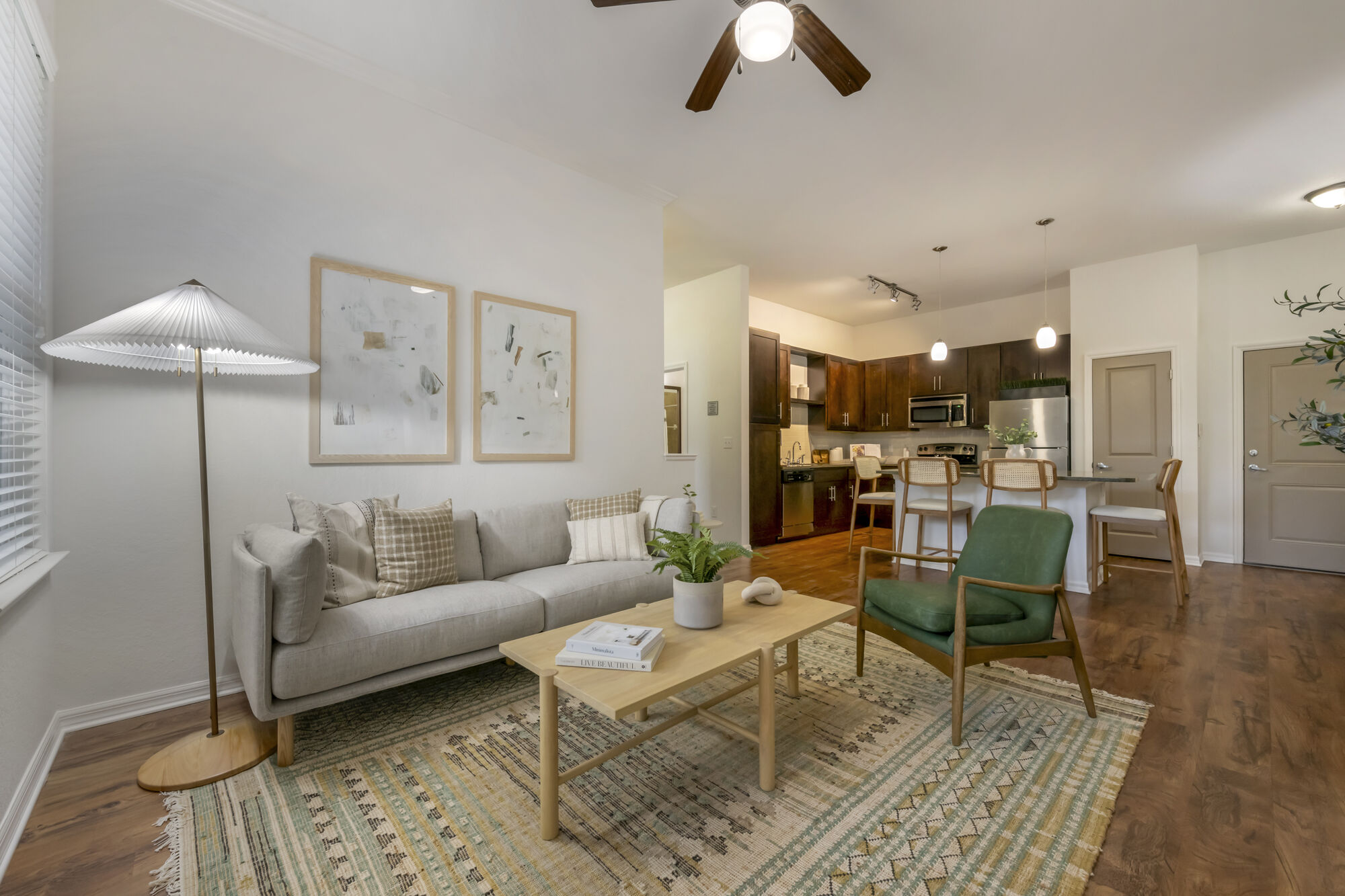 Living room with couch seating, wood-style flooring, designer lighting, and open access to the kitchen